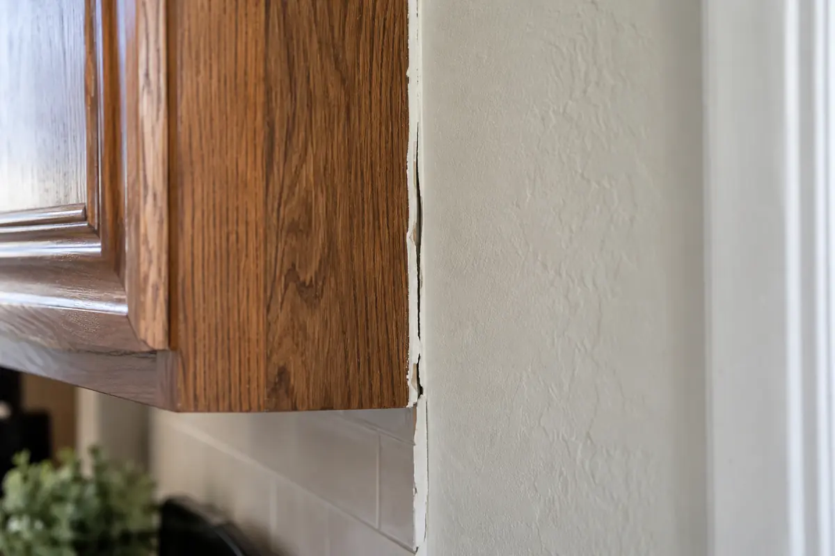 Opening in the caulk seam between a cabinet and painted wall