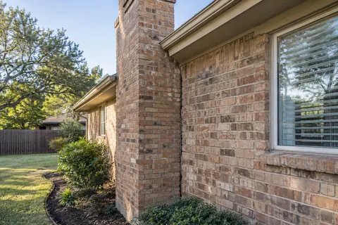 Brick chimney beside a one-story home with a visible junction gap