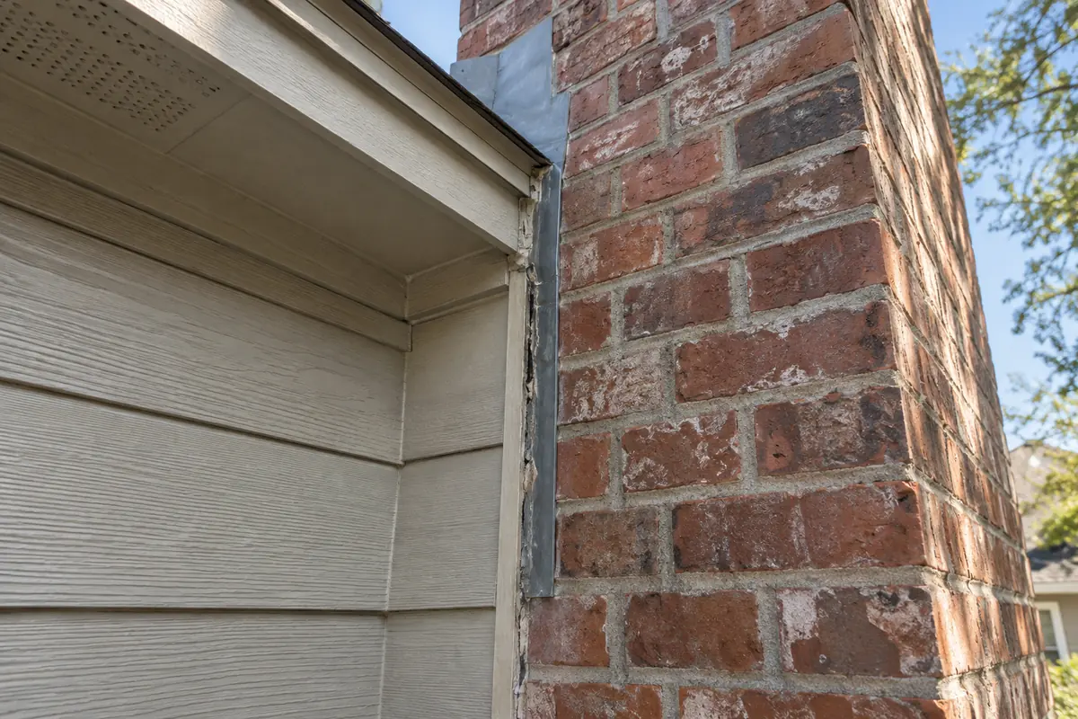 Narrow gap at the junction between a brick chimney and house siding