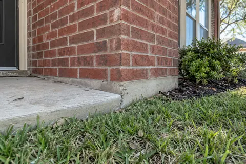Small triangular chip at the concrete slab corner of a brick home