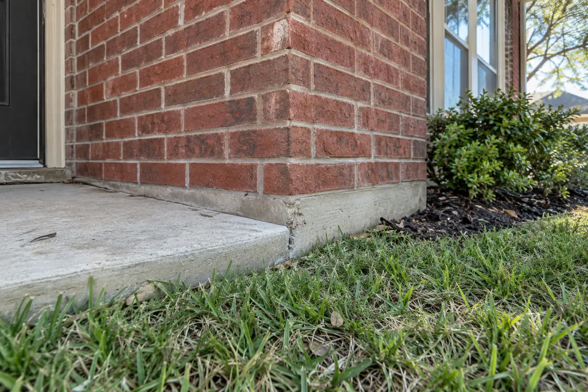 Small triangular chip at the concrete slab corner of a brick home