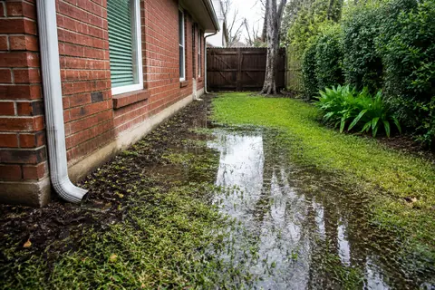 Illustrative yard drainage beside a brick home