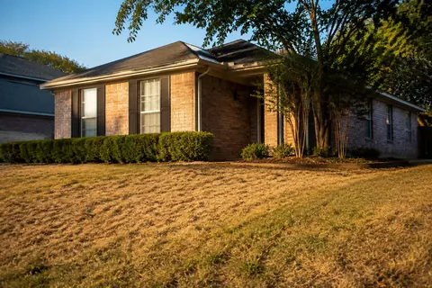 Dry lawn and soil beside a brick house, illustrative image