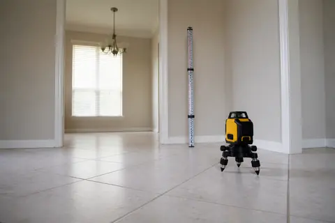 Floor-elevation measuring instrument and survey rod on a tiled residential floor, illustrative image
