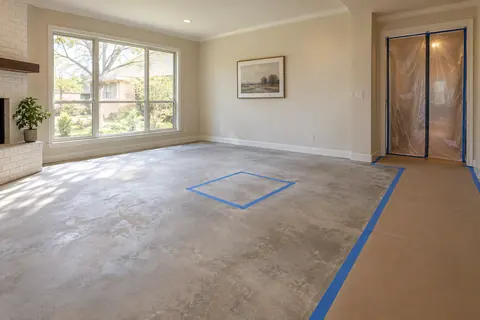 Cleared living room with a taped floor access location, protected walkway and plastic doorway partition