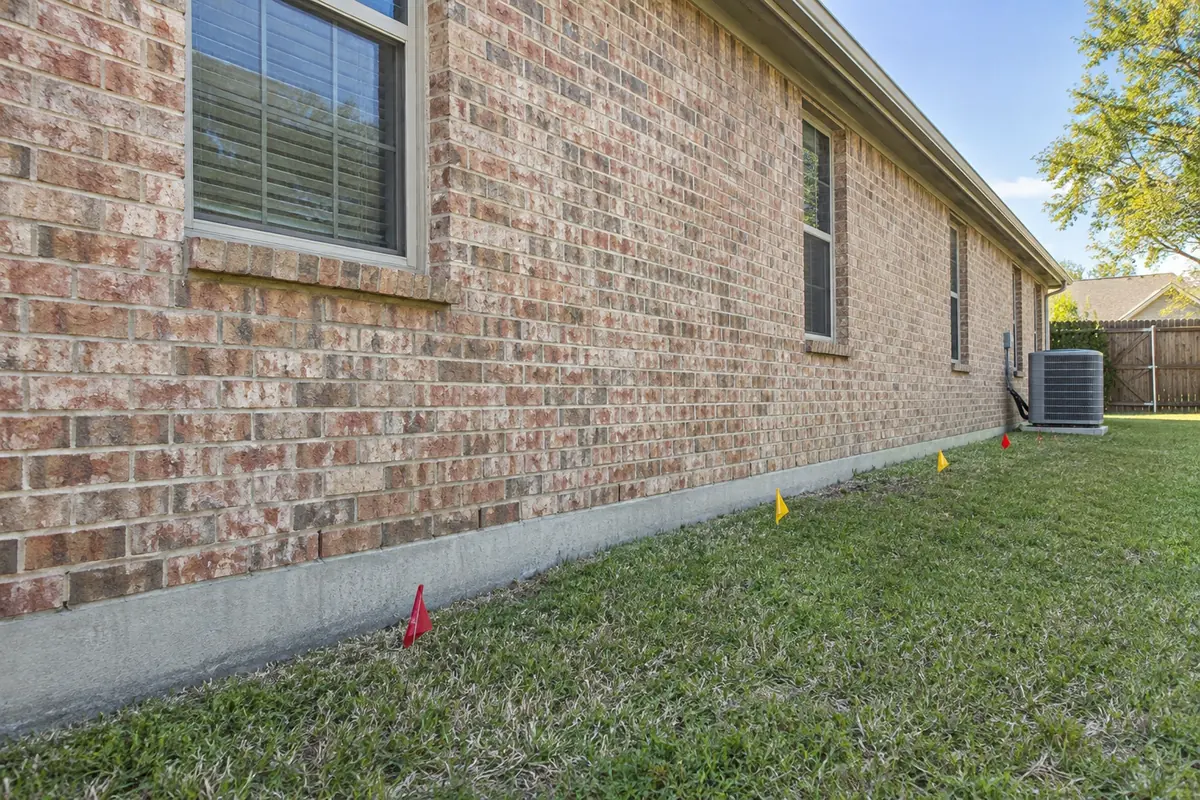 Accessible side yard along a brick home with temporary planning flags