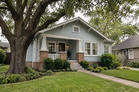 Older blue raised bungalow with front steps and a brick foundation skirt