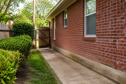 Clear outdoor access path beside a brick house, illustrative image