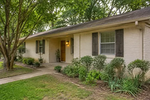 Older cream-brick home with a shaded front porch, illustrative image