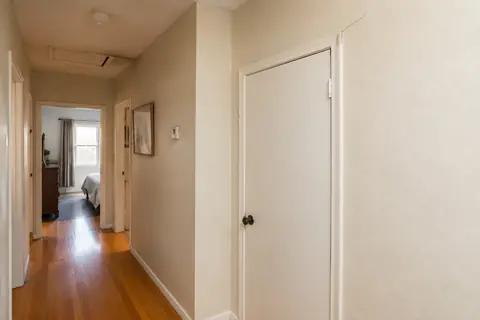 Small diagonal wall crack and trim separation above an interior hallway door, illustrative image