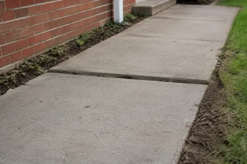 Two concrete walkway panels with an uneven seam, illustrative image