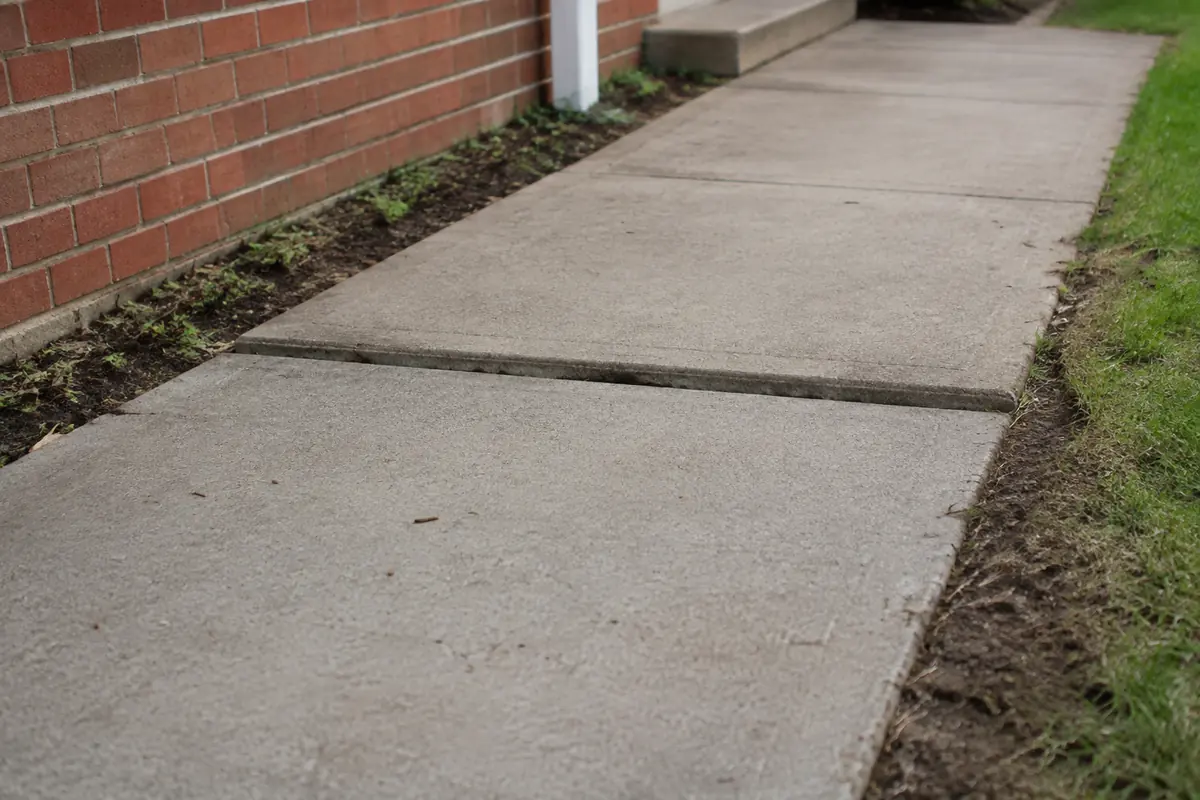 Two concrete walkway panels with an uneven seam, illustrative image